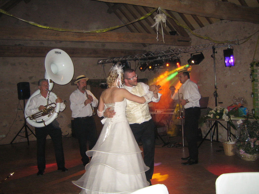 L'orchestre jazz joue la musique du lancement de la soirée dansante du mariage. Les mariés qui dansent et l'orchestre sont à proximité du DJ qui attend la fin de la chanson pour lancer la soirée dansante.